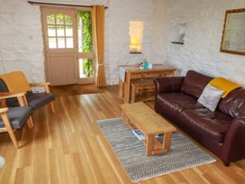 A sitting room with wooden table and chairs a brown leather sofa and a door with windows at Babes Cottage in Perranwell near Goonhavern