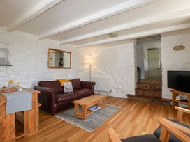 A living room with a leather sofa wooden coffee table and a television at Babes Cottage in Perranwell near Goonhavern
