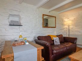 A living room with a brown leather sofa a wooden table with bread a bottle and a carton and a floor lamp at Babes Cottage in Perranwell near Goonhavern