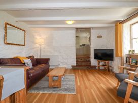 A living room with a brown leather sofa wooden coffee table flat screen tv and armchair at Babes Cottage in Perranwell near Goonhavern