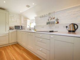 A kitchen with beige cabinets wooden floor microwave kettle and hanging utensils at Babes Cottage in Perranwell near Goonhavern