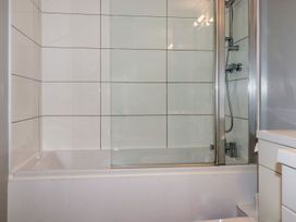 A bathroom with a bathtub and glass shower screen at Babes Cottage in Perranwell near Goonhavern