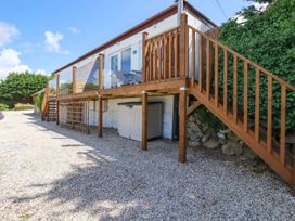 An outdoor area with a raised wooden deck and stairs leading to a building surrounded by gravel at The Lookout in Perranwell near Goonhavern