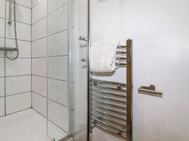 A shower area with white tiled walls and a chrome towel rack with a white towel at The Lookout in Perranwell near Goonhavern