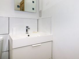A bathroom sink with a faucet soap and a cup under a mirror at The Lookout in Perranwell near Goonhavern