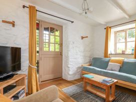 A sitting room with a blue sofa wooden coffee table and television at Hollies Cottage Perranwell near Goonhavern