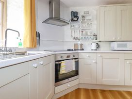 A kitchen with cream cabinets a stainless steel oven a microwave kettle and toaster at Hollies Cottage in Perranwell near Goonhavern