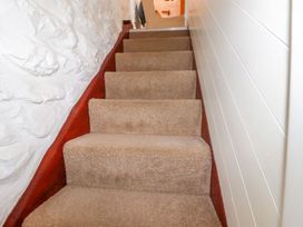A carpeted staircase with white textured wall on the left and white paneled wall on the right at Hollies Cottage in Perranwell near Goonhavern