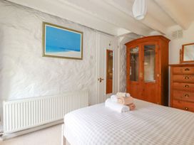 A bedroom with a bed with towels on it a wooden wardrobe a chest of drawers and a radiator at Hollies Cottage in Perranwell near Goonhavern