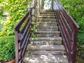 Stone stairs with wooden railings surrounded by green plants at Hollies Cottage in Perranwell near Goonhavern