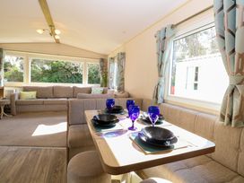 A dining area with a table set with blue glasses and black plates beside a window with patterned curtains and a living room with a beige sofa at 4 Foxburrow Hang in Fritton near Belton Norfolk