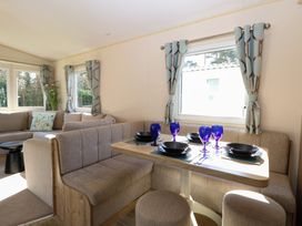 A dining area with a table set with blue glasses and black dishes next to a beige seating area at 4 Foxburrow Hang in Fritton near Belton Norfolk