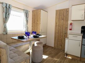 A dining area with corner seating a table set with blue glasses and a wooden door at 4 Foxburrow Hang in Fritton near Belton Norfolk