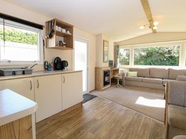 A kitchen area with cabinets and sink next to a living room with a sofa and large windows at 4 Foxburrow Hang in Fritton near Belton Norfolk