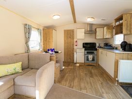 An open plan kitchen and living area with a beige sofa dining table with blue glasses kitchen appliances and wooden flooring at 4 Foxburrow Hang in Fritton near Belton Norfolk