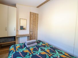 A bedroom with a bed covered in a giraffe patterned blanket and towels on top a wardrobe a mirror and a wooden door at 4 Foxburrow Hang in Fritton near Belton Norfolk