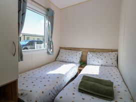 A bedroom with two single beds and a window with curtains at 4 Foxburrow Hang in Fritton near Belton Norfolk