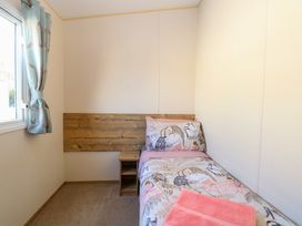A small bedroom with a single bed a wooden headboard a nightstand and a window with curtains at 4 Foxburrow Hang in Fritton near Belton Norfolk