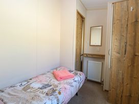 A small bedroom with a single bed with patterned bedding a pink towel a wall mirror a radiator and a wooden wardrobe at 4 Foxburrow Hang in Fritton near Belton Norfolk