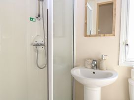 A bathroom with a shower cubicle a sink with soap dispensers and a mirror at 4 Foxburrow Hang in Fritton near Belton Norfolk