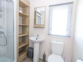 A bathroom with a shower cubicle sink mirror wooden shelves toilet and window blinds at 4 Foxburrow Hang in Fritton near Belton Norfolk