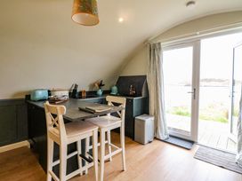 A kitchen area with two high chairs a countertop toaster and double glass door leading outside at Creags in Cullipool Isle Of Luing