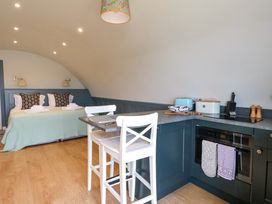 A bedroom with a bed and pillows near a kitchen with a countertop and two white chairs at Creags Cullipool Isle Of Luing