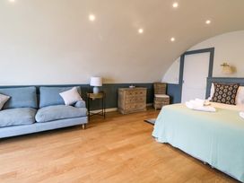 A bedroom with a blue sofa a bed with pillows a wooden chest of drawers and wicker chair at Creags Cullipool Isle Of Luing