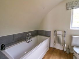 A bathroom with a bathtub a towel rack a toilet and a window at Creags Cullipool Isle Of Luing