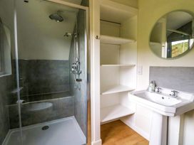 A bathroom with a walk in shower a white sink with a mirror and open shelving at Creags Cullipool Isle Of Luing