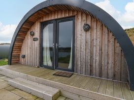 A wooden cabin with curved roof and glass double doors on a wooden porch at Creags in Cullipool Isle Of Luing