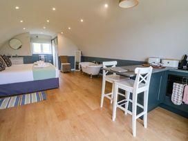 A studio room with a bed towels a bathtub chairs a small kitchen area and a window at Erraid in South Cuan near Cullipool Isle Of Luing