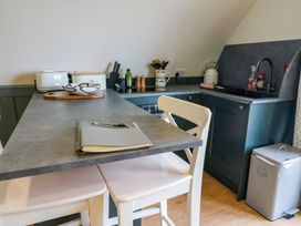 A kitchen with a countertop and two white chairs a toaster knives utensils and a kettle on counters at Erraid in South Cuan near Cullipool Isle Of Luing