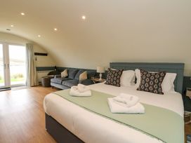 A bedroom with a king bed, patterned pillows, a sofa, and glass doors leading outside at Erraid South Cuan near Cullipool Isle Of Luing