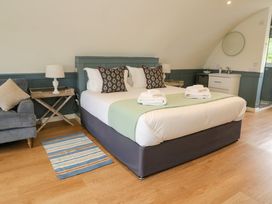 A bedroom with a bed and two pillows a chair a side table with a lamp a striped rug and a sink at Erraid in South Cuan near Cullipool Isle Of Luing