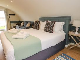 A bedroom with a bed with two towels and pillows a sofa a bedside table with lamp and a window with curtains at Erraid in South Cuan near Cullipool Isle Of Luing