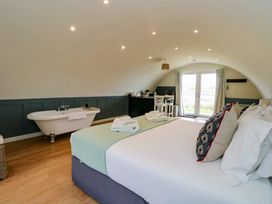 A bedroom with a bed towels a bathtub small kitchenette and double doors leading outside at Erraid South Cuan near Cullipool Isle Of Luing