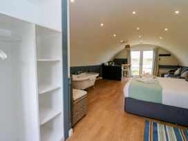 A bedroom with a bed towels open closet bathtub seating area kitchenette and glass doors at Erraid in South Cuan near Cullipool Isle Of Luing