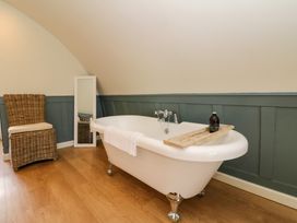 A bathroom with a freestanding bathtub wooden floor wicker chair and a standing mirror at Erraid in South Cuan near Cullipool Isle Of Luing