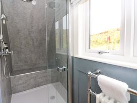 A bathroom shower with glass door a towel rail and a window showing an outside view at Erraid South Cuan near Cullipool Isle Of Luing