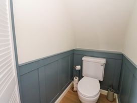 A small bathroom with a white toilet blue paneling on the walls and wooden floor at Erraid in South Cuan near Cullipool Isle Of Luing