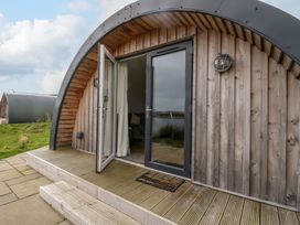 The exterior of a wooden cabin with an arched roof and open glass doors at Insh Cullipool Isle Of Luing