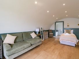 A bedroom with a green sofa a wooden floor a bed and a dresser at Insh Cullipool Isle Of Luing