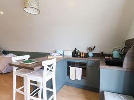 A kitchen area with blue cabinets white chairs a wooden countertop and cooking utensils at Insh Cullipool Isle Of Luing