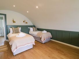A bedroom with two single beds with pillows blankets and folded towels at Insh Cullipool Isle Of Luing