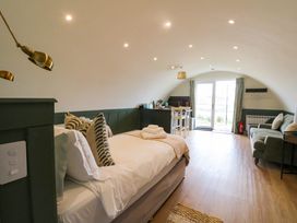 A bedroom with a bed sofa table chairs and a kitchenette at Insh Cullipool Isle Of Luing