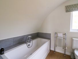 A bathroom with a bathtub a towel rack a window and a toilet at Insh Cullipool Isle Of Luing