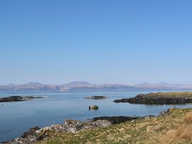 A small boat on calm water near rocky shorelines with mountains in the background at Sula Cullipool Isle Of Luing
