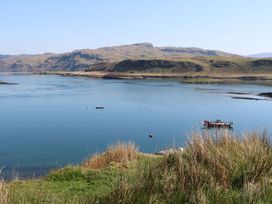 A coastal landscape with boats on water and grassy hills in the background at Sula Cullipool Isle Of Luing