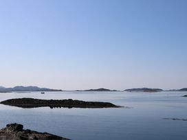 A calm sea with small rocky islands and a boat in the distance at Sula in Cullipool Isle Of Luing